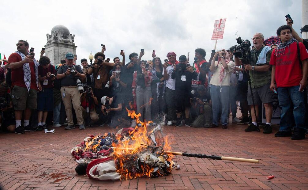 Los manifestantes queman una bandera estadounidense frente a Union Station. Foto: AFP