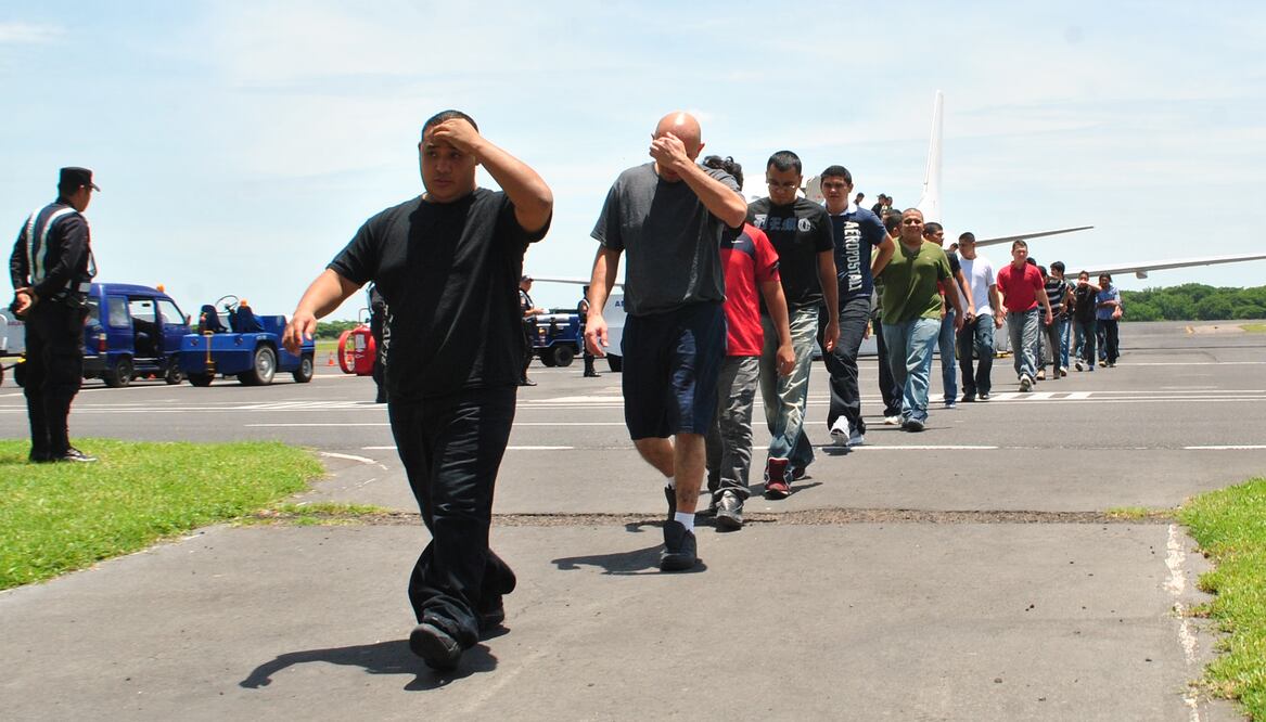 Un grupo de salvadoreños deportados desde EU camina por la pista del aeropuerto internacional Monseñor Oscar Arnulfo Romero y Galdámez, de El Salvador, rumbo a una oficina migratoria. Fotografía cortesía del periódico EL MUNDO, de San Salvador