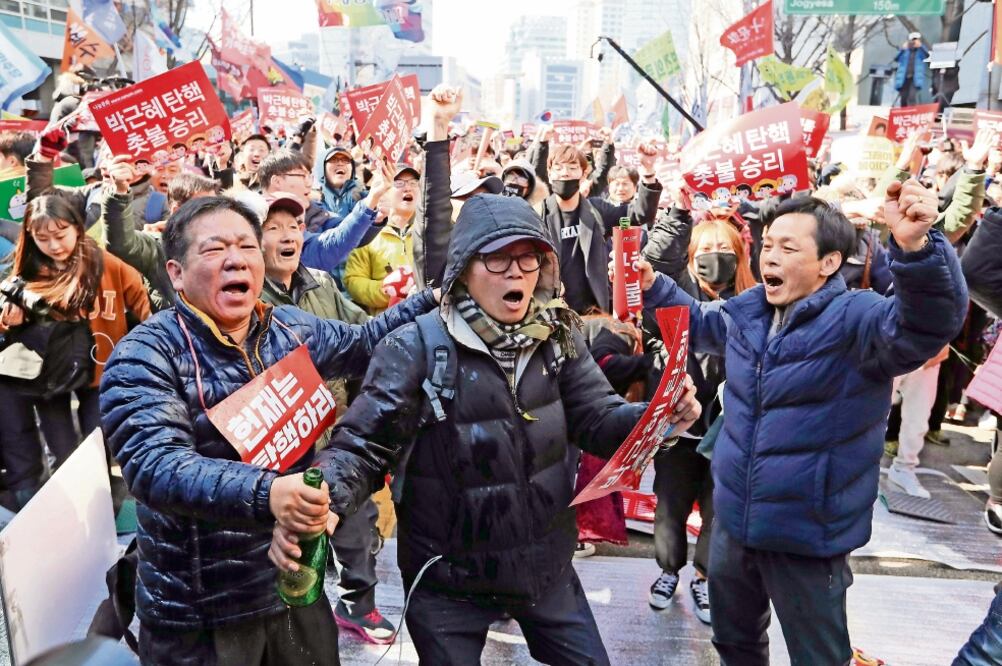 Manifestantes celebran tras darse a conocer el fallo, en Seúl, por el cual la presidenta Park Geun-hye queda destituida y pierde la inmunidad (LEE JIN-MAN. AP)
