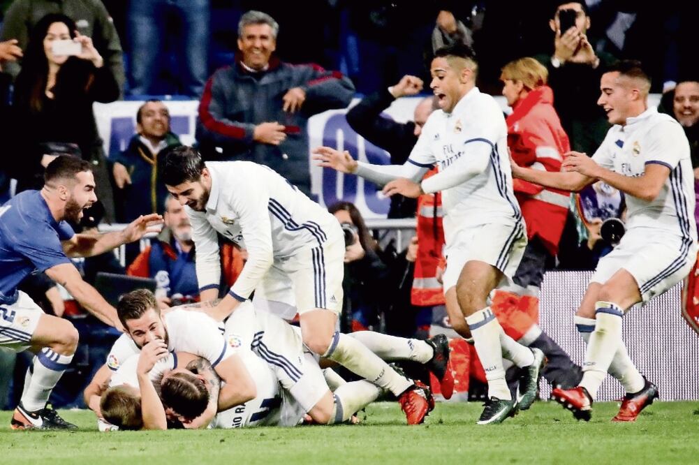El defensa del Real Madrid Sergio Ramos (en el suelo) fue felicitado por su gol que dio el triunfo en el Bernabéu (JUANJO MARTÍN. EFE)