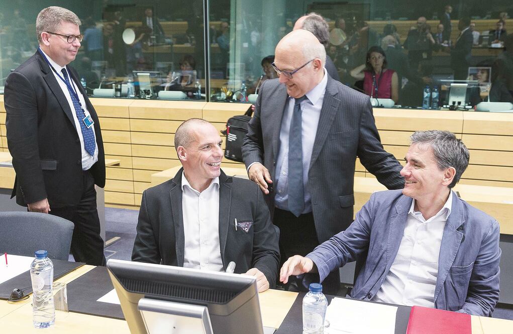 El ministro griego de Finanzas, Yanis Varoufakis (izq.). conversa con su par francés, Michel Sapin (de pie), en Bruselas (PHILIPPE WOJAZER. REUTERS)