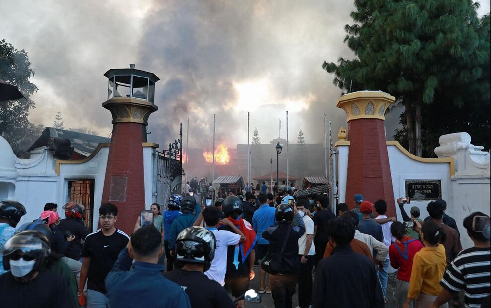 Manifestantes se agolpan mientras el humo se eleva desde la Casa Presidencial en llamas, en Katmandú, Nepal, el martes 9 de septiembre de 2025, un día después de la represión policial contra las manifestaciones por la prohibición de las redes sociales y la corrupción gubernamental. Foto: AFP