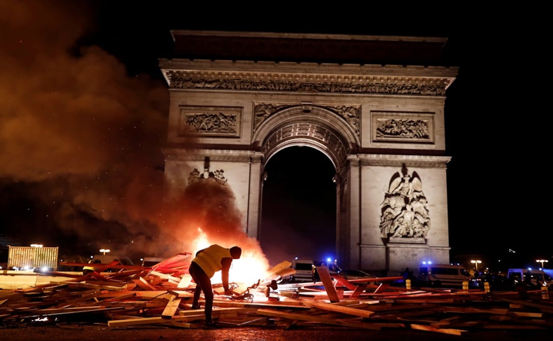 A protester is seen next to a burning barricade during a "Yellow vest" protests against higher fuel prices, on the Champs-Elysees in Paris, France - Photo: Benoit Tessier/REUTERS