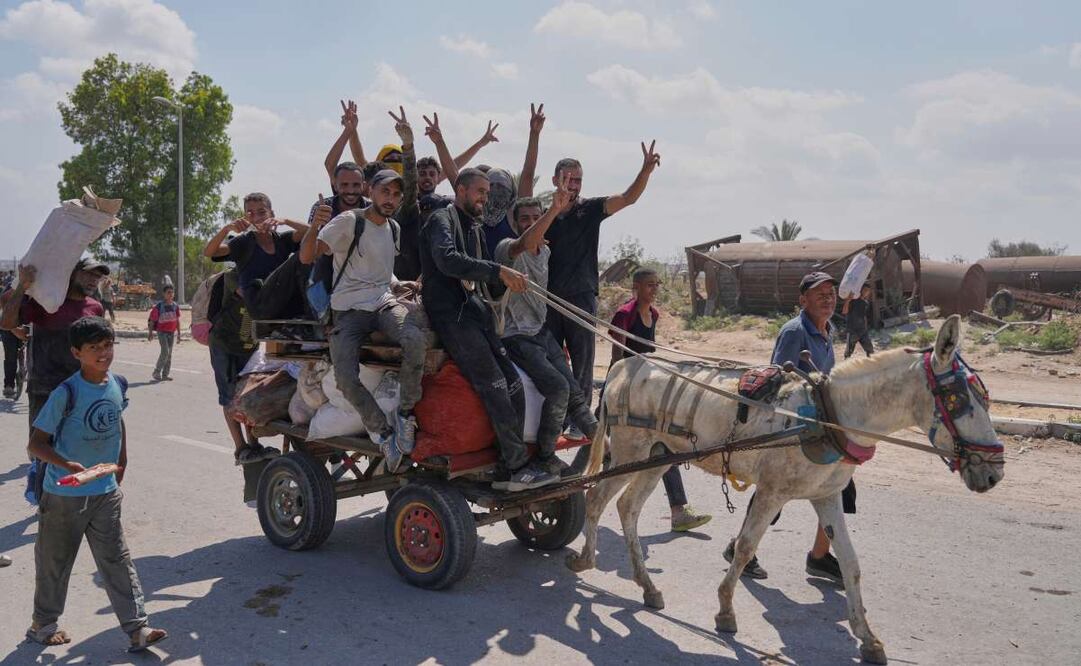 Palestinos saludan a la cámara mientras llevan paquetes de ayuda humanitaria cerca de un centro de distribución de la Fundación Humanitaria de Gaza, operado por la organización respaldada por Estados Unidos, en Netzarim, en el centro de la Franja de Gaza, el lunes 4 de agosto de 2025. Foto: AP