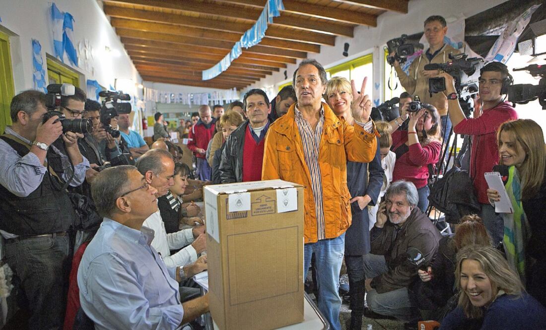 Daniel Scioli (centro), en compañía de su esposa Karina Rab o l l i n i (centroderecha), antes de emitir su voto en una escuela primaria de la localidad de Dique Luján, a 50 kilómetros de Buenos Aires (MARTIN ZABALA. XINHUA)