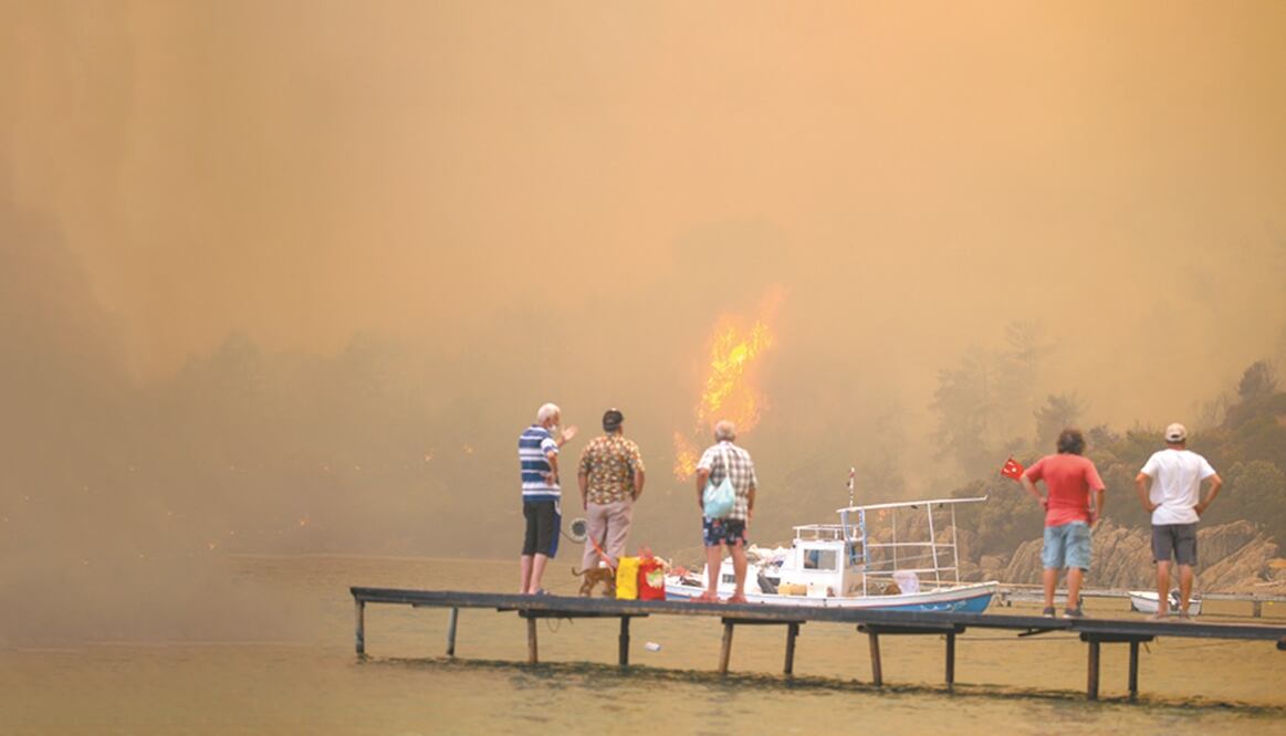 Turistas esperaban ser desalojados del área de Mazi envuelta en humo, mientras los incendios forestales bajaban la colina hacia la orilla del mar, en Bodrum, Turquía. Foto: Emre Tazegul. AP