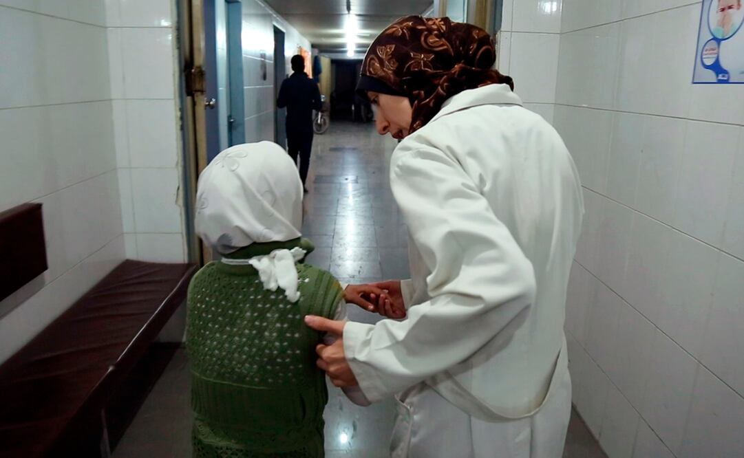 La doctora Amani, derecha, lleva a una niña dentro de un hospital en Siria en una escena del documental nominado al Oscar "The Cave". Foto: AP