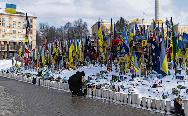 Una ucraniana arregla flores depositadas en un monumento improvisado a los soldados de Ucrania y extranjeros caídos en la Plaza de la Independencia, en el centro de Kiev, durante la invasión rusa. Foto: Henry Nicholls / AFP