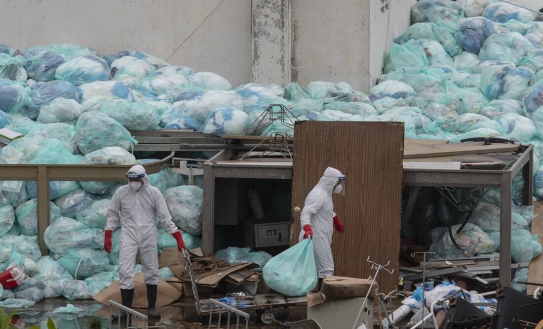 Medical workers using protective equipment dispose of trash bags containing hazardous biological waste - Photo: Felix Marquez/AP