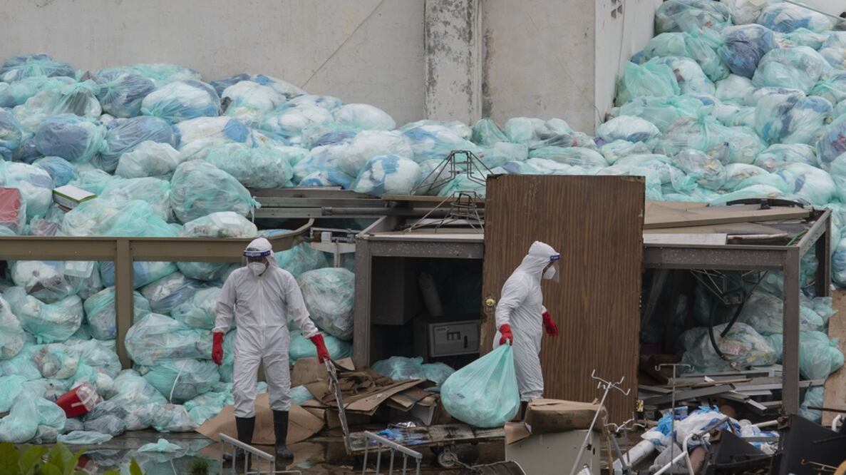 Medical workers using protective equipment dispose of trash bags containing hazardous biological waste - Photo: Felix Marquez/AP