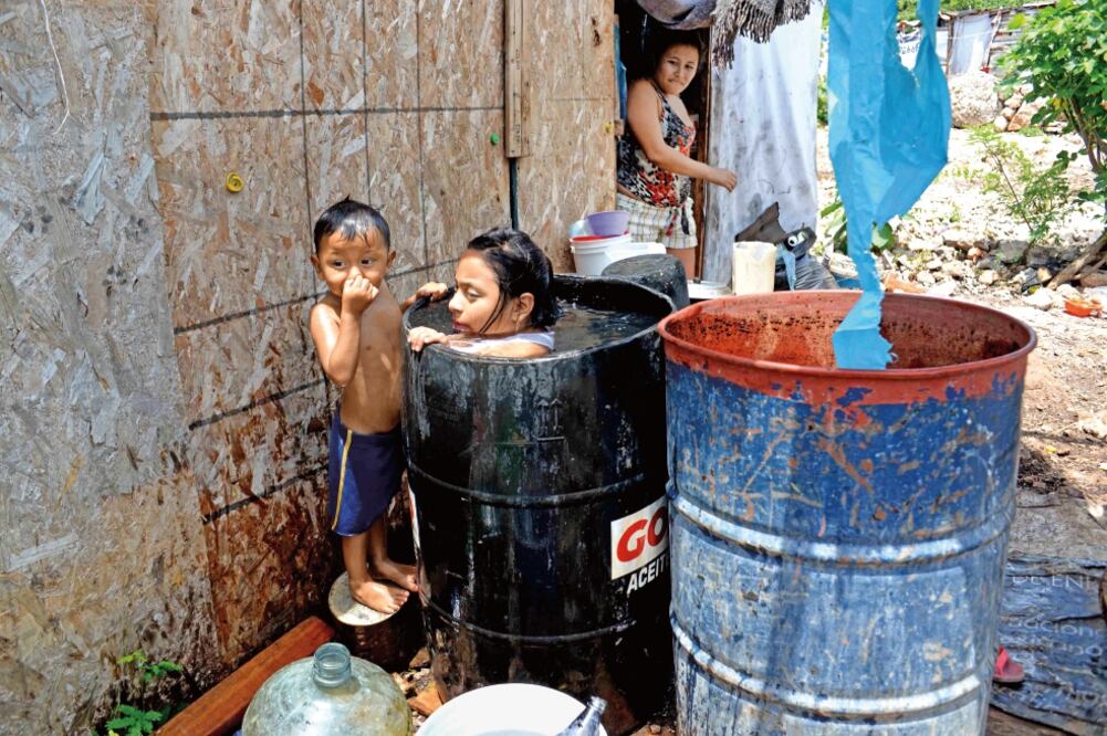 Al no tener agua potable, los niños se remojan en el barril para aguantar las altas temperaturas. (CUAUHTÉMOC MORENO. EL UNIVERSAL)