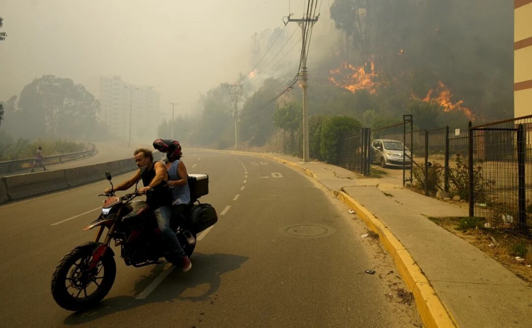 Residentes evacúan en una motocicleta entre incendios forestales en Viña del Mar, Chile, el 3 de febrero de 2024. Foto: AP