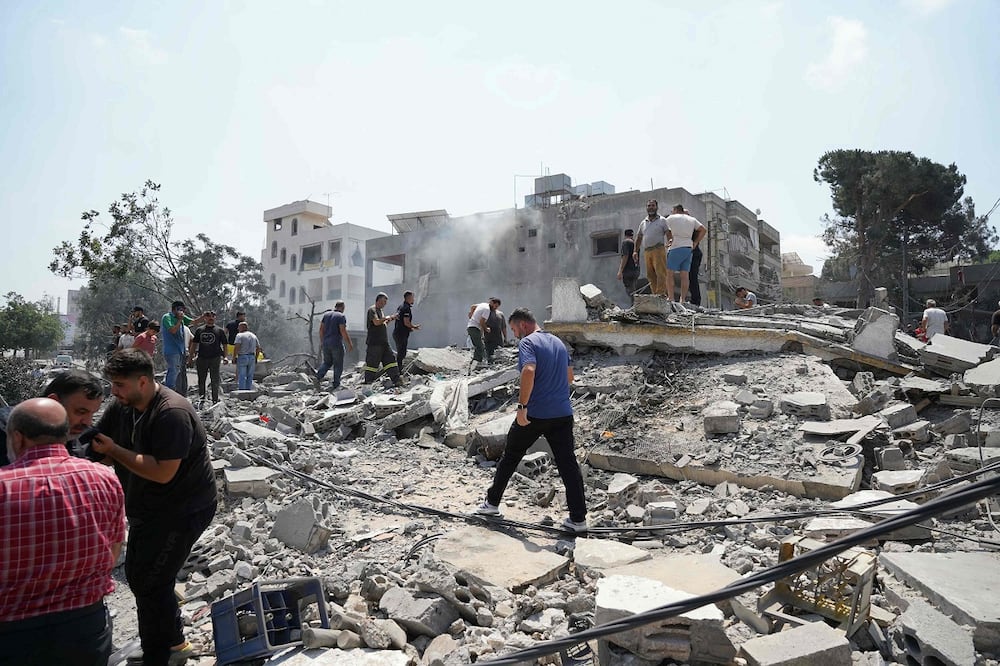 Equipos de emergencia y residentes inspeccionan el lugar de un ataque aéreo israelí contra un barrio de la localidad de Deir al-Zahrani, en el sur del Líbano. Foto: AFP