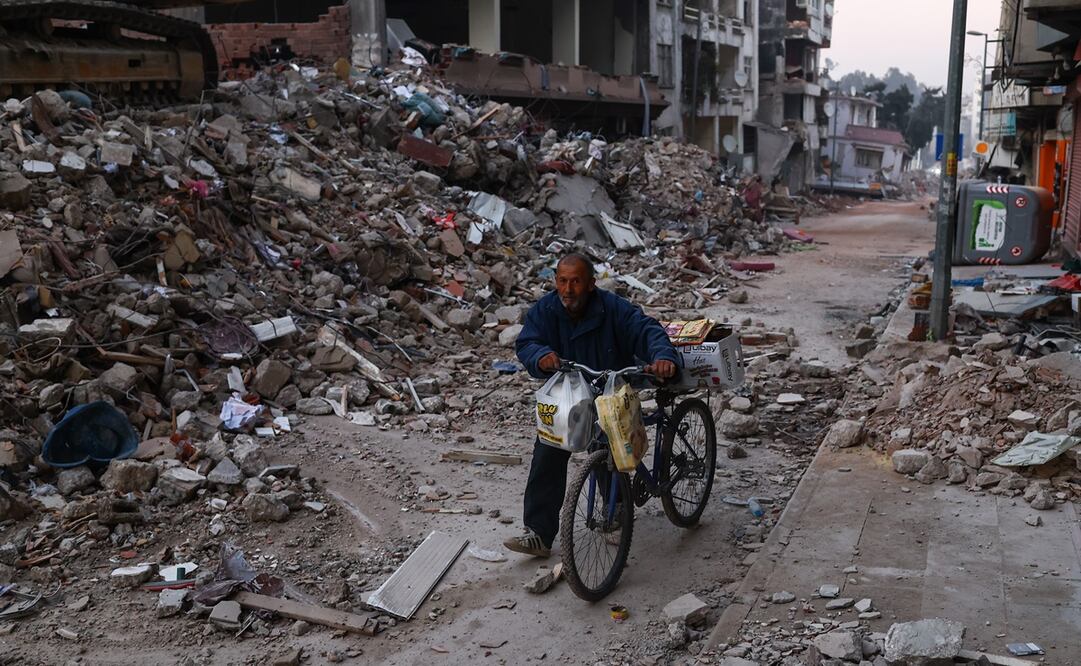 Un hombre y su bicicleta en el sitio de los edificios derrumbados después de un fuerte terremoto, en Hatay, Turquía, el 14 de febrero de 2023. Foto: EFE