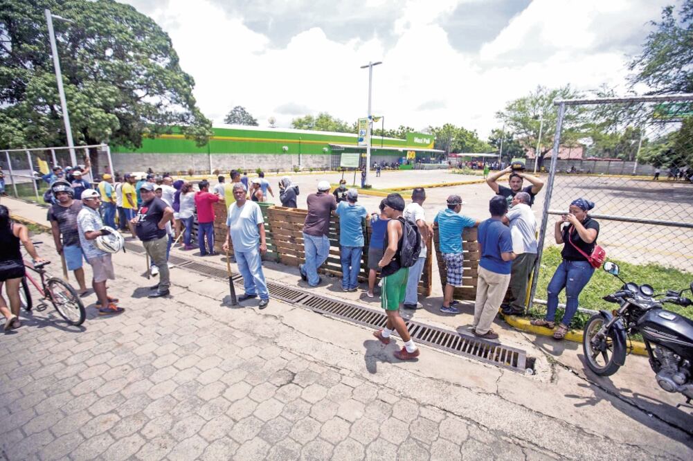 Personas vigilan las instalaciones de un supermercado, después de un saqueo ocurrido durante la madrugada en otro local, en Masaya (JORGE TORRES. EFE)