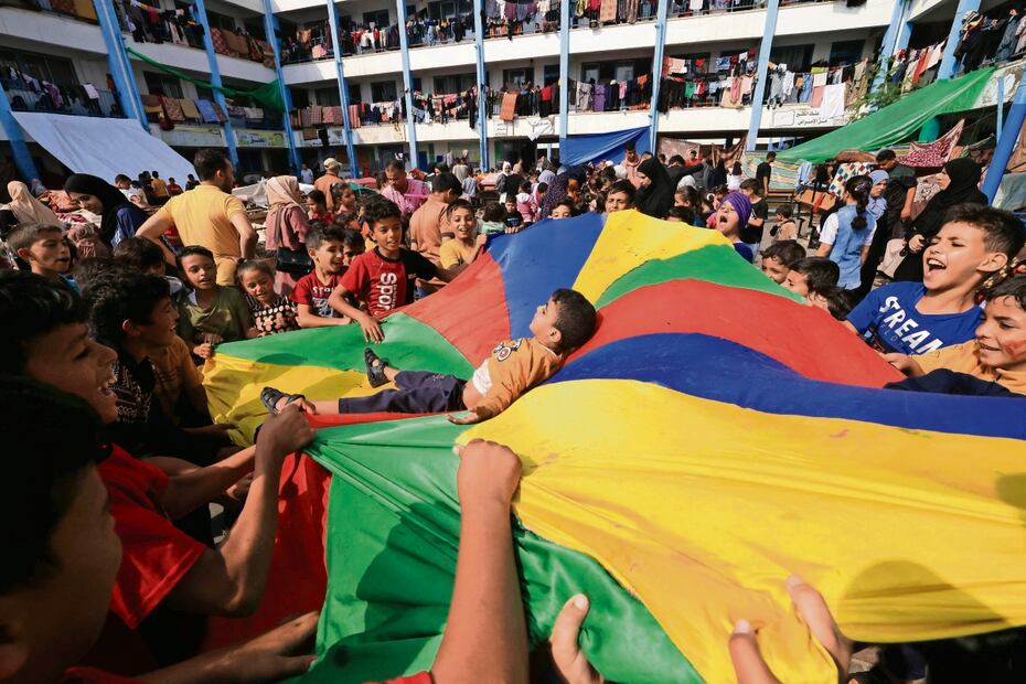 Niños palestinos que han huido de sus hogares por los ataques israelíes se divierten con juegos organizados por trabajadores humanitarios. Foto: Mahmud Jamones | AFP