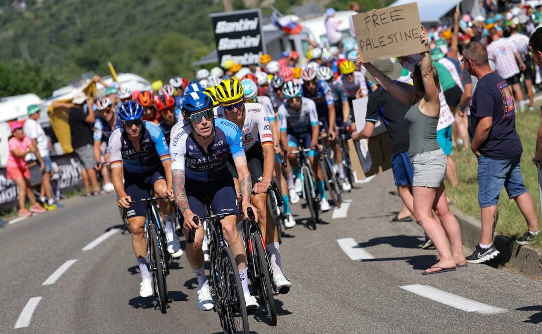 Un espectador sostiene un cartel que dice "Palestina libre" mientras el ciclista israelí británico del equipo Premier Tech, Jake Stewart, lidera el grupo, en el Tour de Francia. Foto: AFP