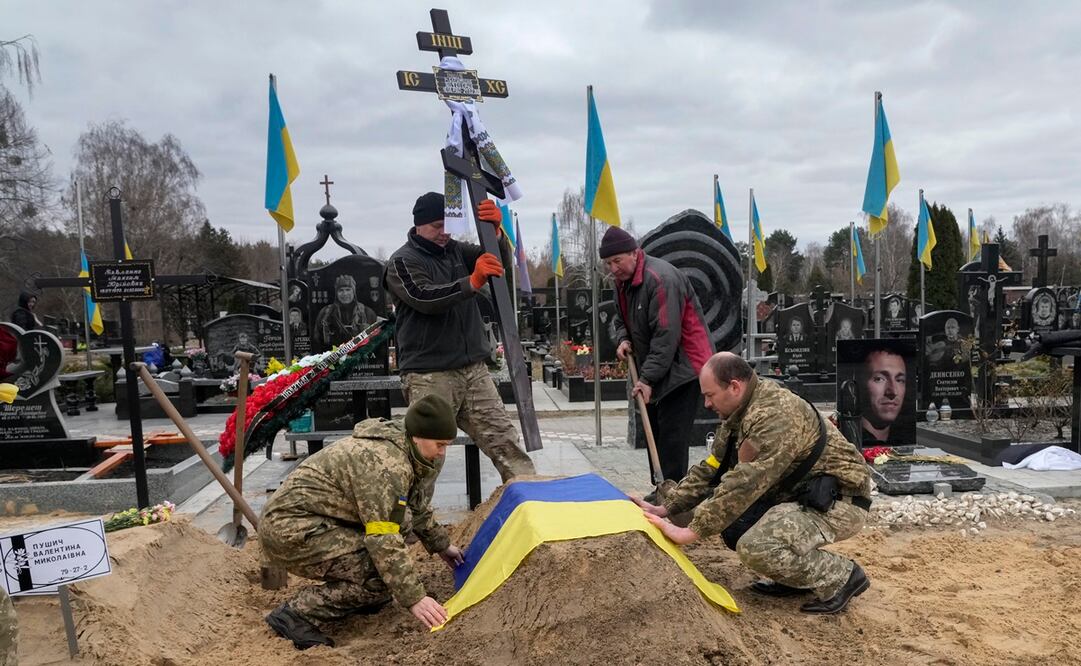Los trabajadores se persignan tras empujar los cuerpos a la zanja. Foto: AP
