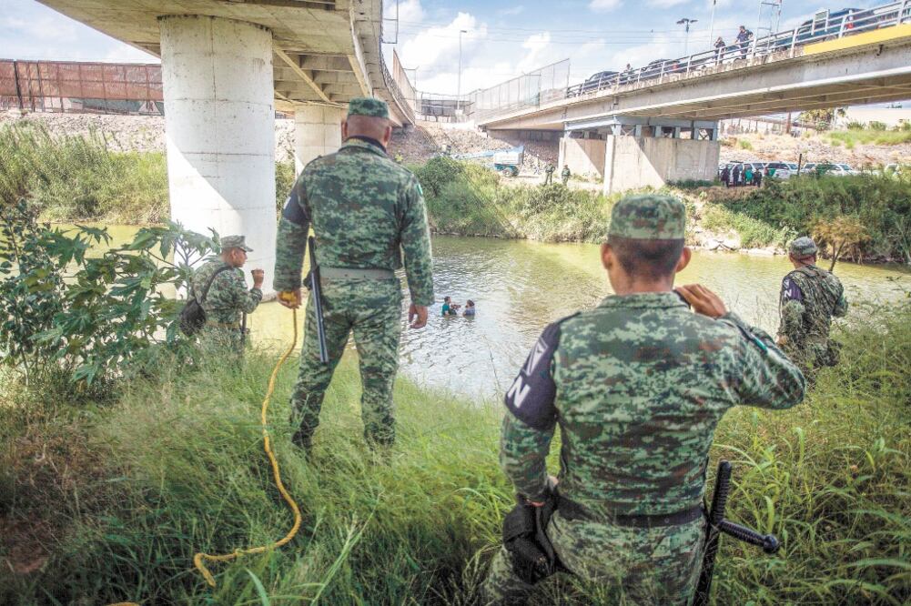 Elementos de la Guardia Nacional, del lado de Matamoros, y de la Patrulla Fronteriza, del lado estadounidense, observan a migrantes cruzar el río Bravo. Foto/CARLOS OGAZ. AFP