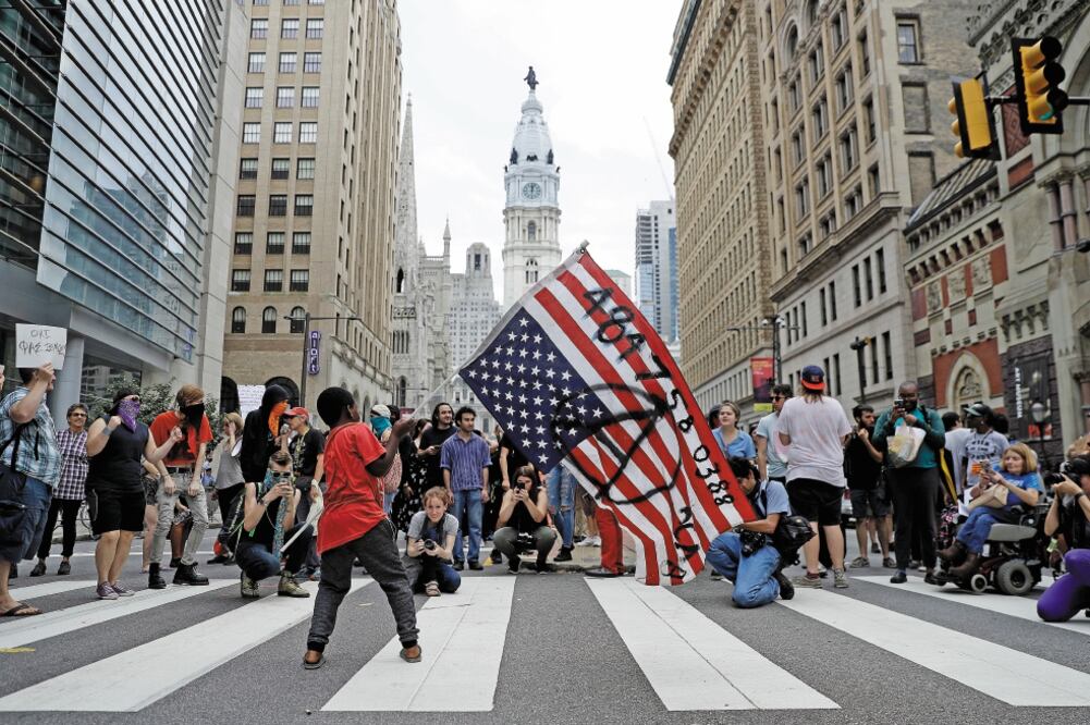 Un niño ondea una bandera de Estados Unidos durante una manifestación contra el gobierno de Donald Trump, en Philadelphia. (MATT SLOCUM. AP)