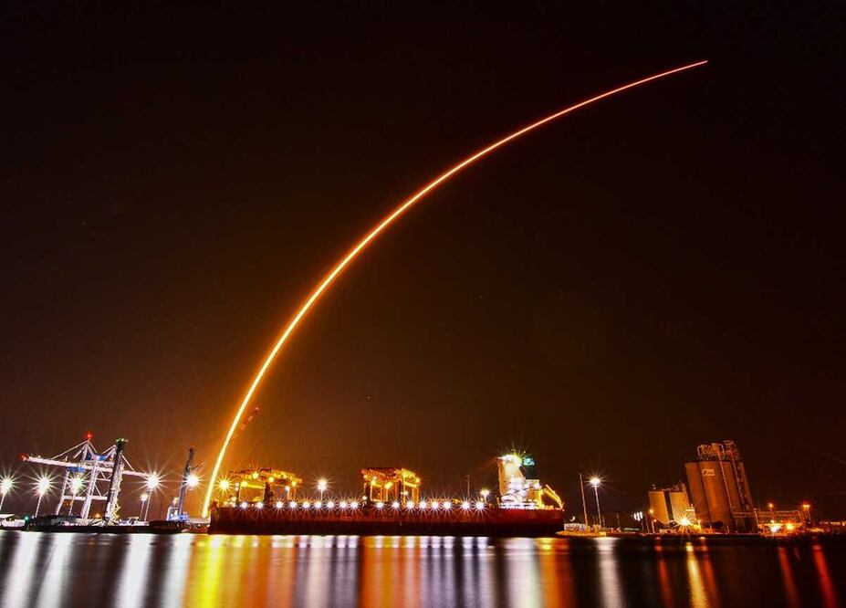 La racha de un SpaceX Falcon 9 se arquea sobre el carguero Saga Faith, descargando madera en Port Canaveral, Florida. Foto: AP/Malcolm Denemark