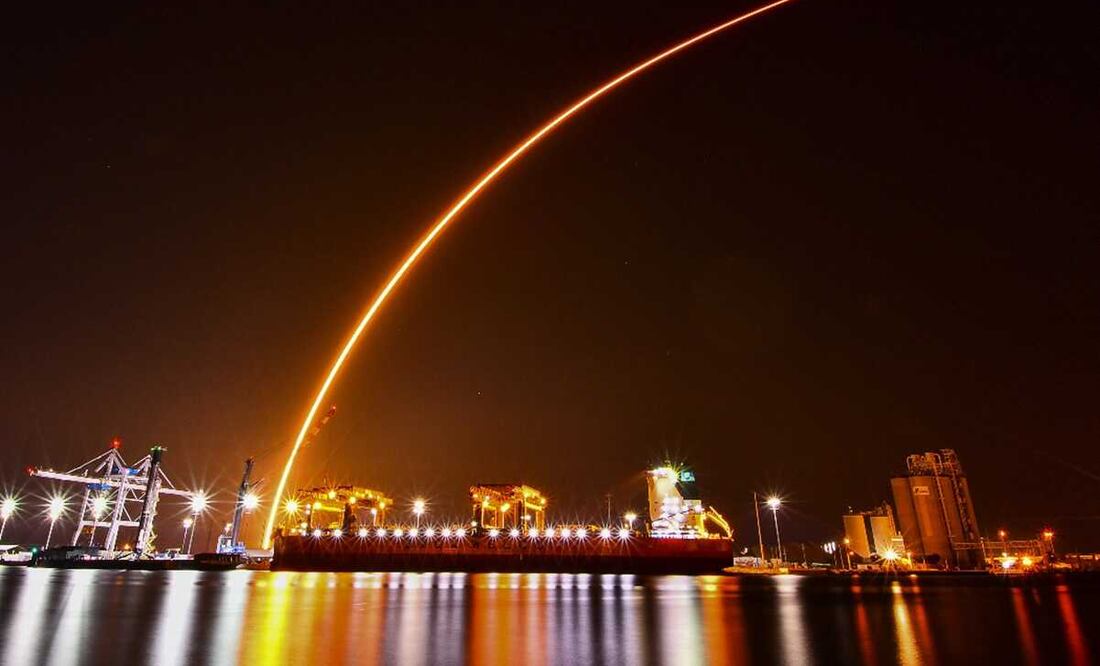 La racha de un SpaceX Falcon 9 se arquea sobre el carguero Saga Faith, descargando madera en Port Canaveral, Florida. Foto: AP/Malcolm Denemark