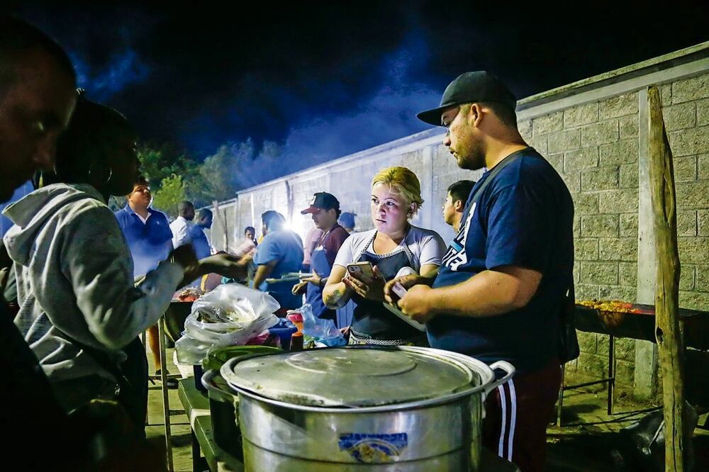 Jóvenes migrantes trabajan vendiendo pollos asados y tacos de cecina en un negocio local en la entrada del CMM. Foto: Claus Mendoza | El universal