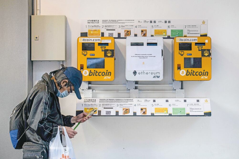 Un hombre camina frente a cajeros automáticos de bitcoin en Hong Kong. La atención sobre la divisa aumentó en 2013 por su uso para lavar dinero (ANTHONY WALLACE. AFP)