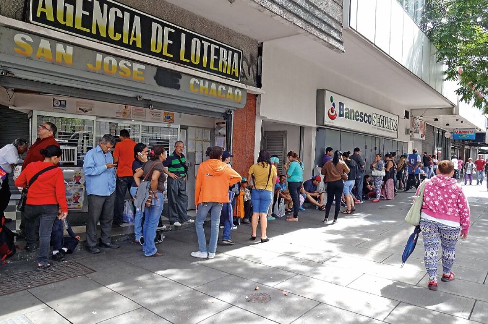 Las largas colas y lenta espera fuera de tiendas y supermercados son habituales en Caracas: los ciudadanos tienen asignado un día a la semana para abastecerse de su canasta básica, cuyos productos son los que más escasean (JOSÉ MELÉNDEZ. EL UNIVERSAL)