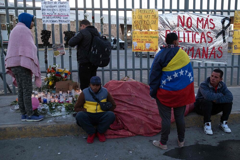 Migrantes junto a un altar improvisado por los 38 que perdieron la vida en el incendio del 27 de marzo en un centro de detención en Ciudad Juárez. FOTO: GUILLERMO ARIAS.  AFP