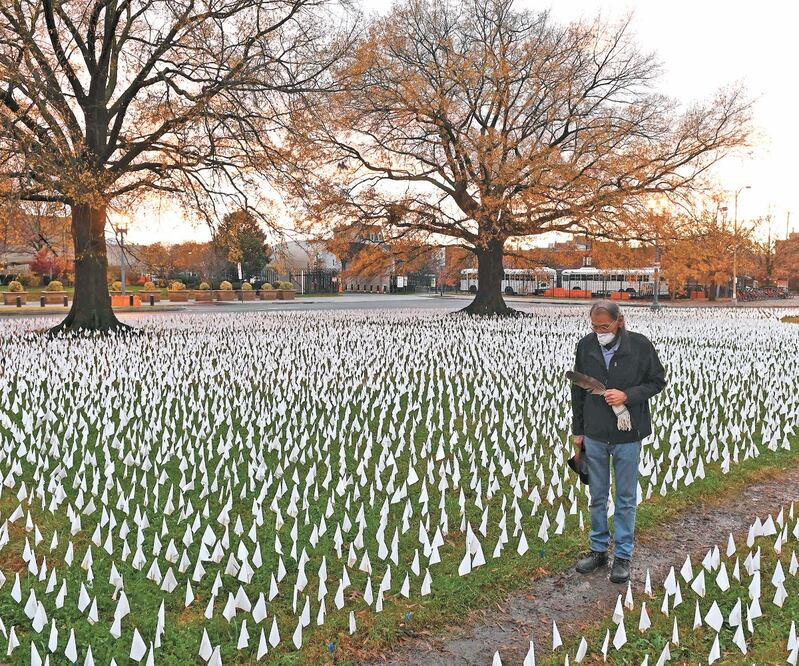 Un estadounidense en una instalación artística en Washington. Cada bandera re presenta una víctima por el Covid-19. Foto: ROBERTO SCHMIDT. AFP