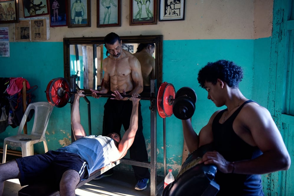 El excampeón de culturismo nicaragüense sordo Walter Pérez (C) ayuda a un joven mientras entrena en su gimnasio en Santa Teresa, departamento de Carazo, Nicaragua, el 22 de febrero de 2024. Foto: AFP