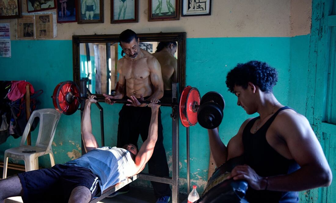 El excampeón de culturismo nicaragüense sordo Walter Pérez (C) ayuda a un joven mientras entrena en su gimnasio en Santa Teresa, departamento de Carazo, Nicaragua, el 22 de febrero de 2024. Foto: AFP