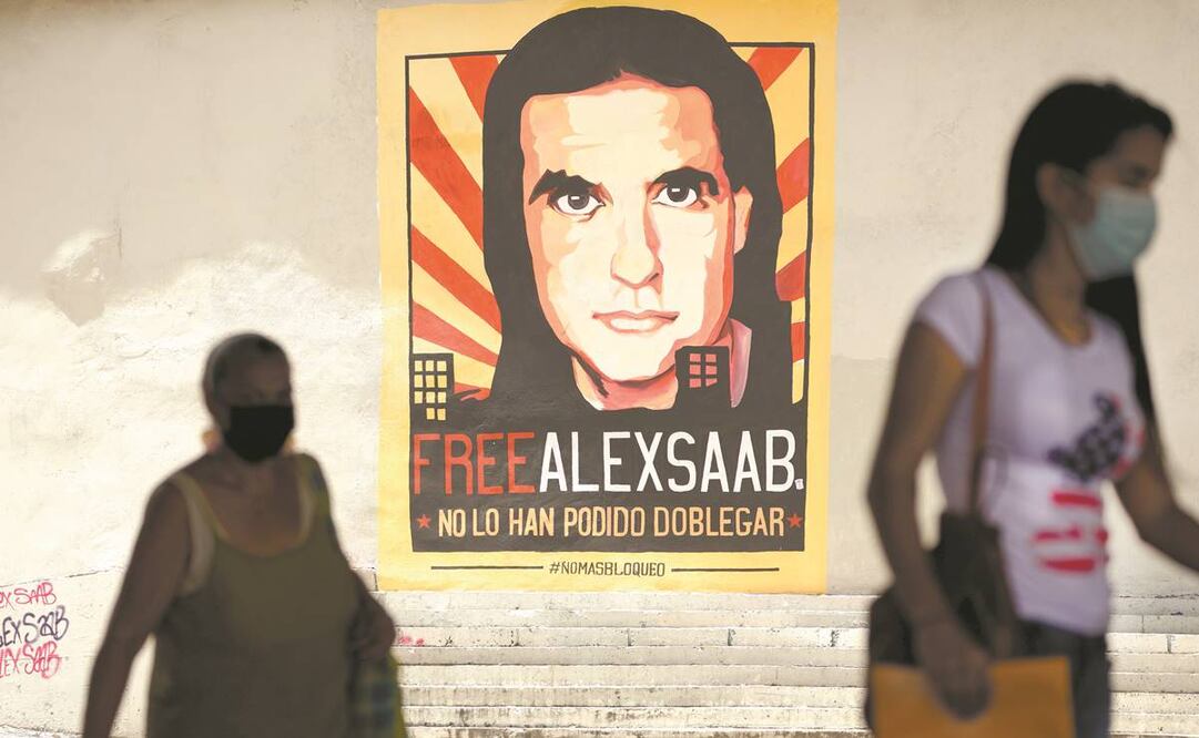 Peatones, cerca de una pancarta en la que se pide la libertad del empresario Alex Saab, en Caracas. Foto: Ariana Cubillos/ AP.