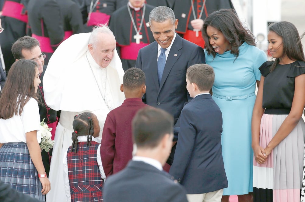 El Papa saluda a un grupo de niños, mientras es observado por el presidente de E U, Barack Obama, y la primera dama, Michelle, en la Base Andrews, en Maryland (KEVIN LAMARQUE. REUTERS)