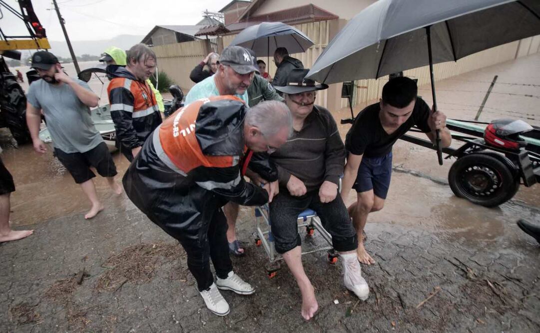 Un grupo de personas ayudan a la evacuación de un adulto mayor en medio de la lluvia este miércoles, en Santa María, Estado de Río Grande del Sur, Brasil. Foto: EFE