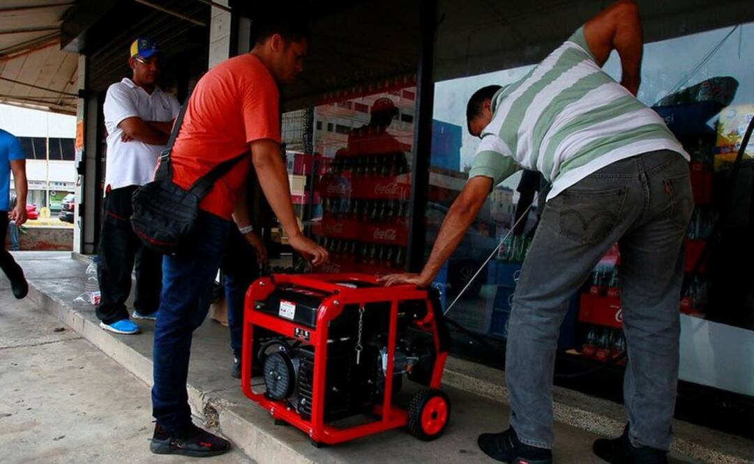 Dos hombre tratan de encender un generador frente a un supermercado de Maracaibo (Foto: Reuters)