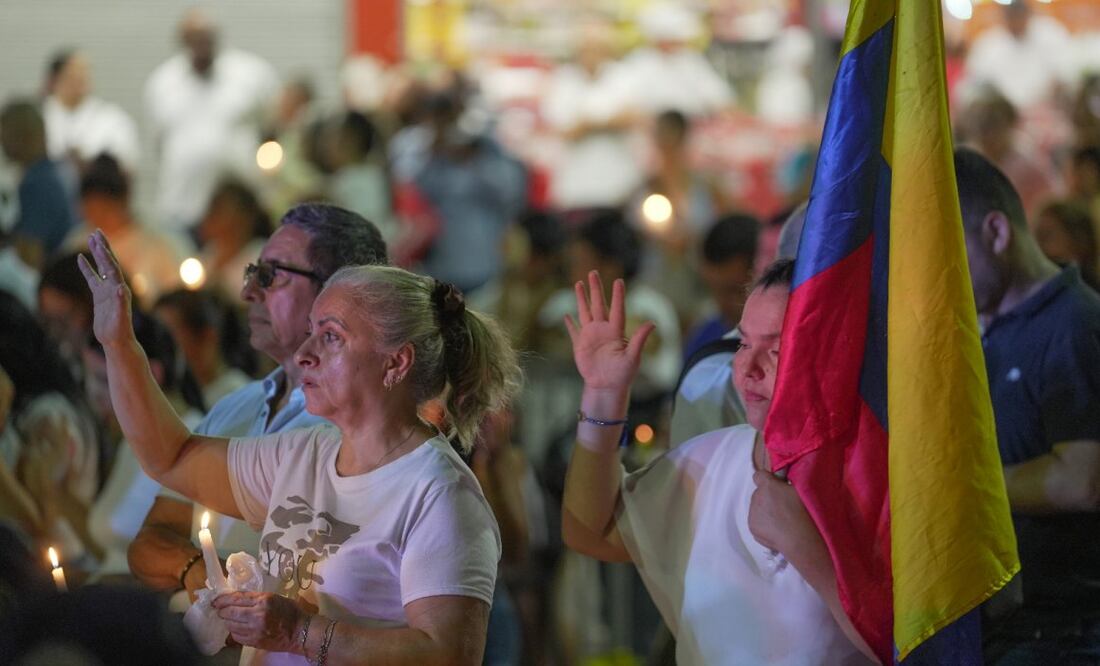 La gente sostiene velas frente a la base aérea de Cali, Colombia, durante una vigilia en honor a las víctimas de un coche bomba que explotó. (24/08/25) Foto: EFE