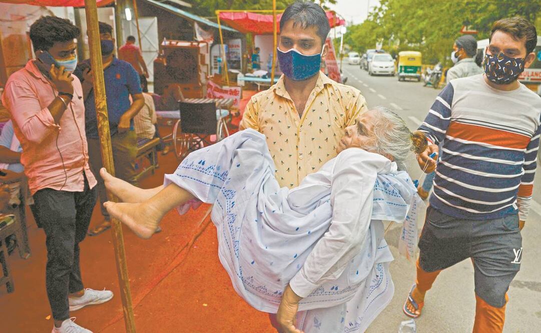 Un familiar lleva a una mujer que requiere oxígeno, en Nueva Delhi. Foto: Arun Sankar. AFP
