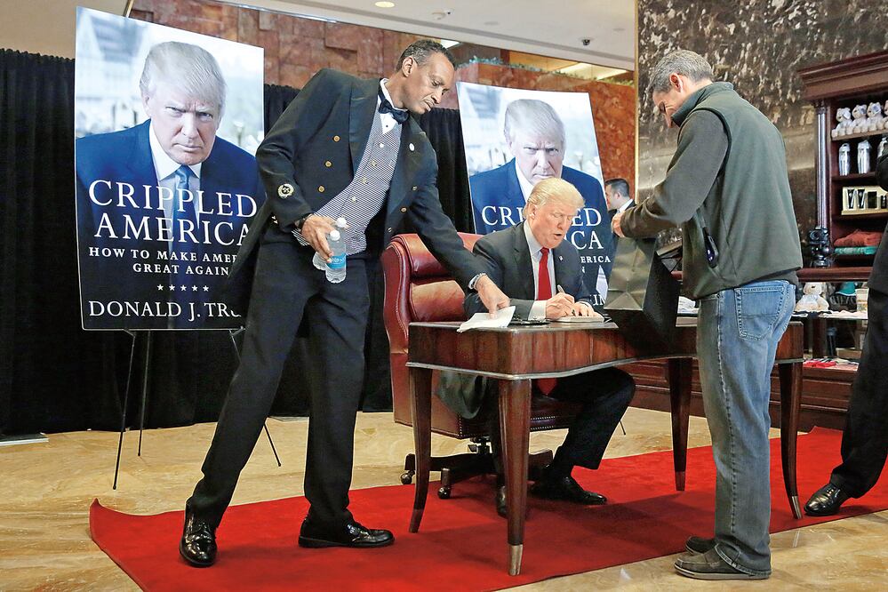 Un empleado lleva una botella de agua a Donald Trump, mientras éste autografía su libro "Crippled America" ( EU incapacitado), en su rascacielos en Nueva York (RICHARD DREW. AP)