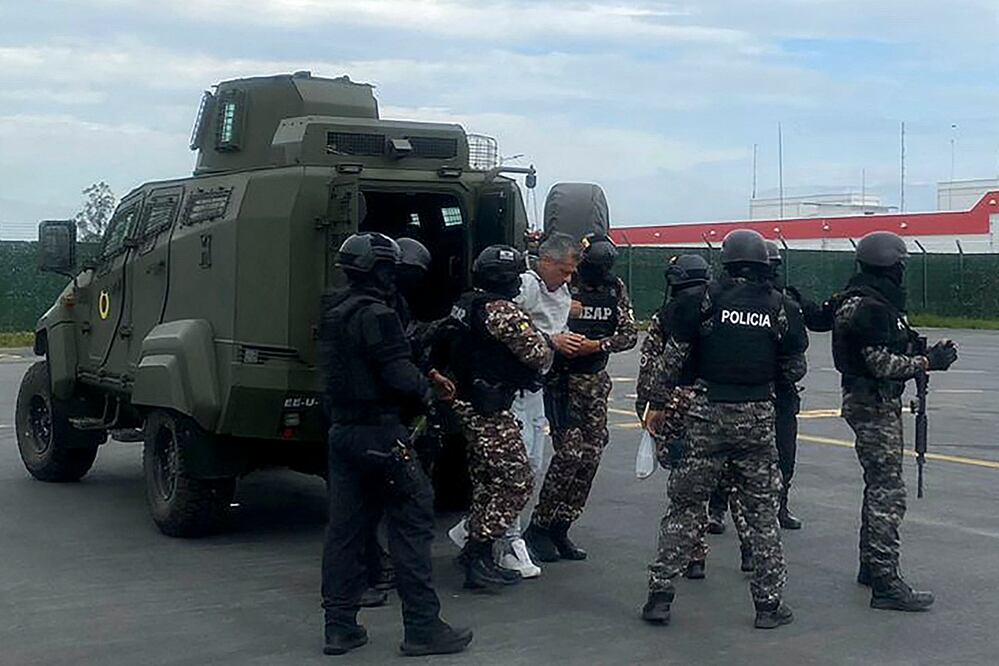Jorge Glas (C) escoltado por miembros de la policía antes de su traslado a la prisión de máxima seguridad La Roca en Guayaquil en el Aeropuerto Internacional Mariscal Sucre. Foto: Policía Ecuatoriana / AFP