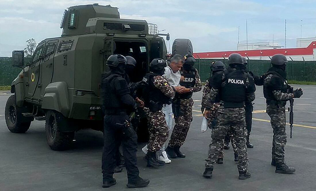 Jorge Glas (C) escoltado por miembros de la policía antes de su traslado a la prisión de máxima seguridad La Roca en Guayaquil en el Aeropuerto Internacional Mariscal Sucre. Foto: Policía Ecuatoriana / AFP