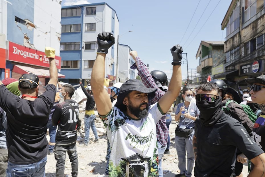Rescatistas y voluntarios levantan los brazos pidiendo silencio durante una operación de rescate en los escombros de un edificio en Pereira, Colombia. FOTO. CARLOS ORTEGA. EFE