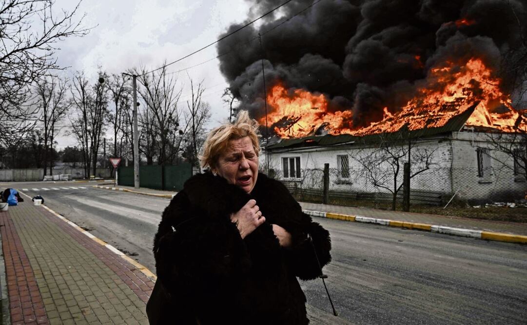 Una ucraniana, frente a una casa en llamas después de ser bombardeada en la ciudad de Irpin, a las afueras de Kiev. Foto: Aris Messinis/AFP