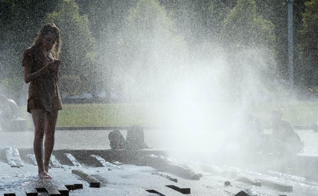 Una mujer se refresca en una fuente en el parque Lustgarten, en Berlin (AP Photo/Markus Schreiber)