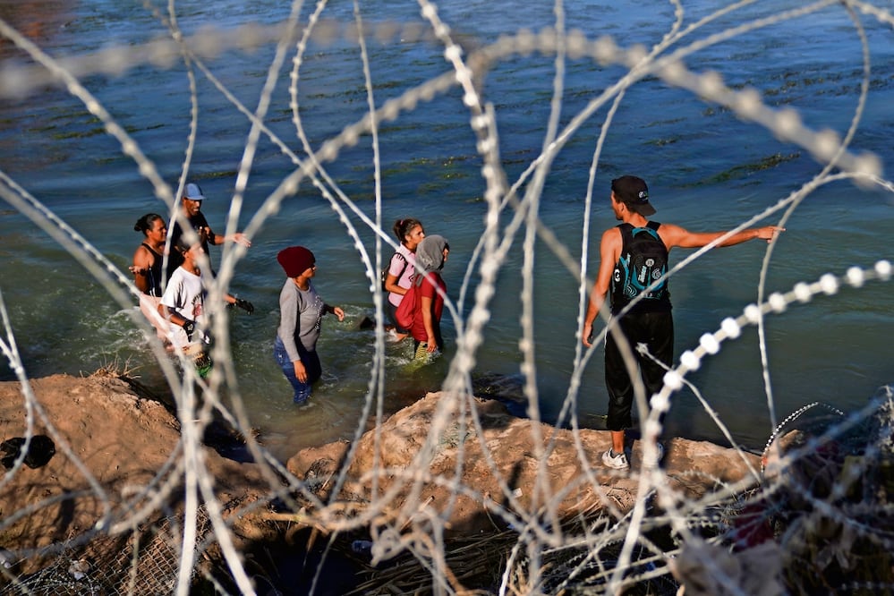Indocumentados caminan por el río Grande a lo largo de un alambrado, mientras intentan cruzar a Estados Unidos desde México. Foto: Eric Gay/ AP