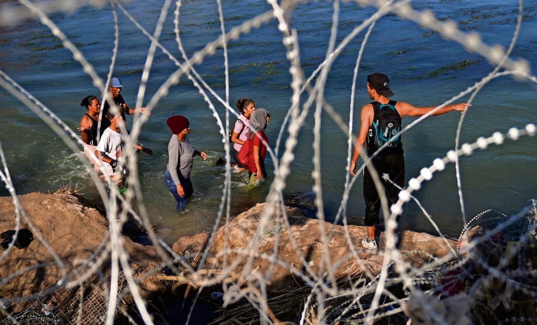 Indocumentados caminan por el río Grande a lo largo de un alambrado, mientras intentan cruzar a Estados Unidos desde México. Foto: Eric Gay. AP