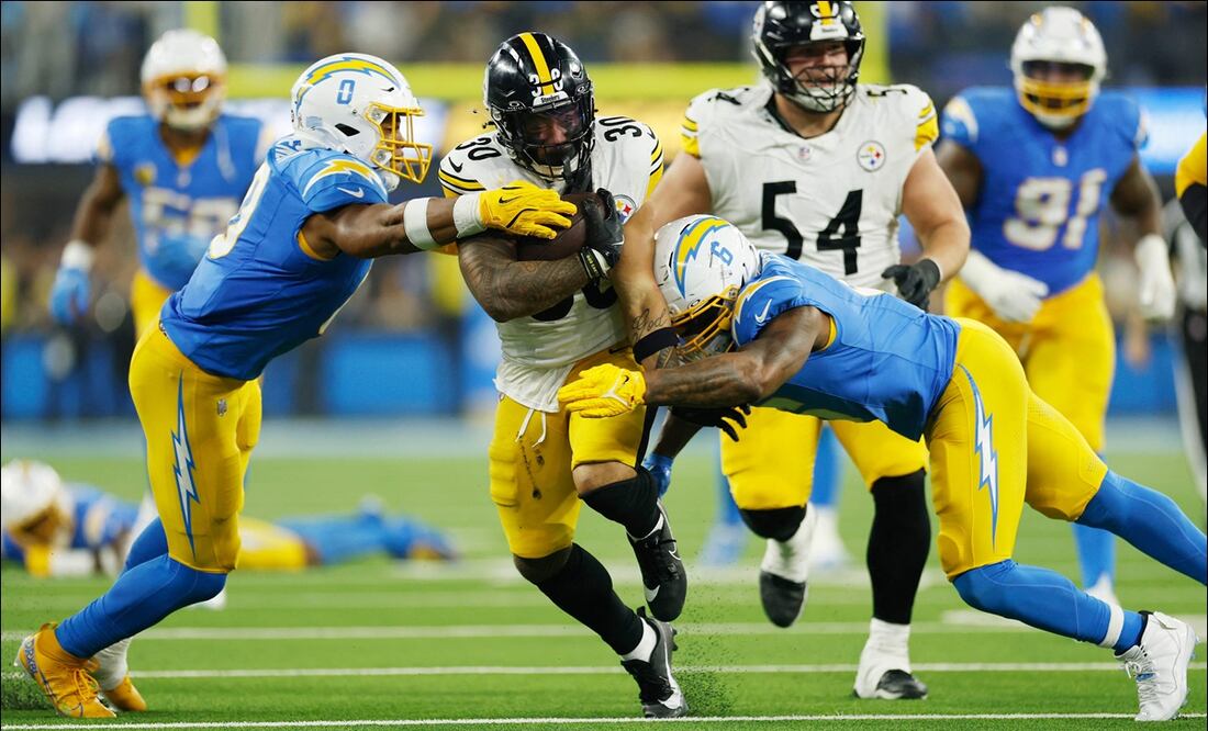 Jaylen Warren (30), de los Pittsburgh Steelers es tacleado por Denzel Perryman (6) and Daiyan Henley (0) de Los Angeles Chargers, durante el tercer cuarto de su partido. FOTO: AFP