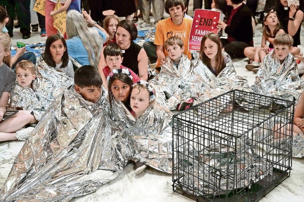 Niños envueltos con mantas de aluminio, emulando a los menores migrantes detenidos en centros en EU, durante una protesta ayer en un edificio del Senado, en Washington, contra la separación de familias. Foto: AFP