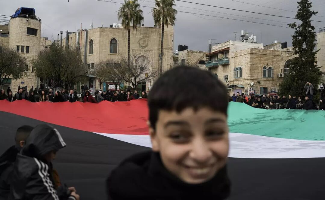 Gente sostiene una bandera palestina en la plaza del Pesebre, cerca de la Basílica de la Natividad, considerada por la tradición como el lugar de nacimiento de Jesús, en la ciudad cisjordana de Belén. Foto: AP